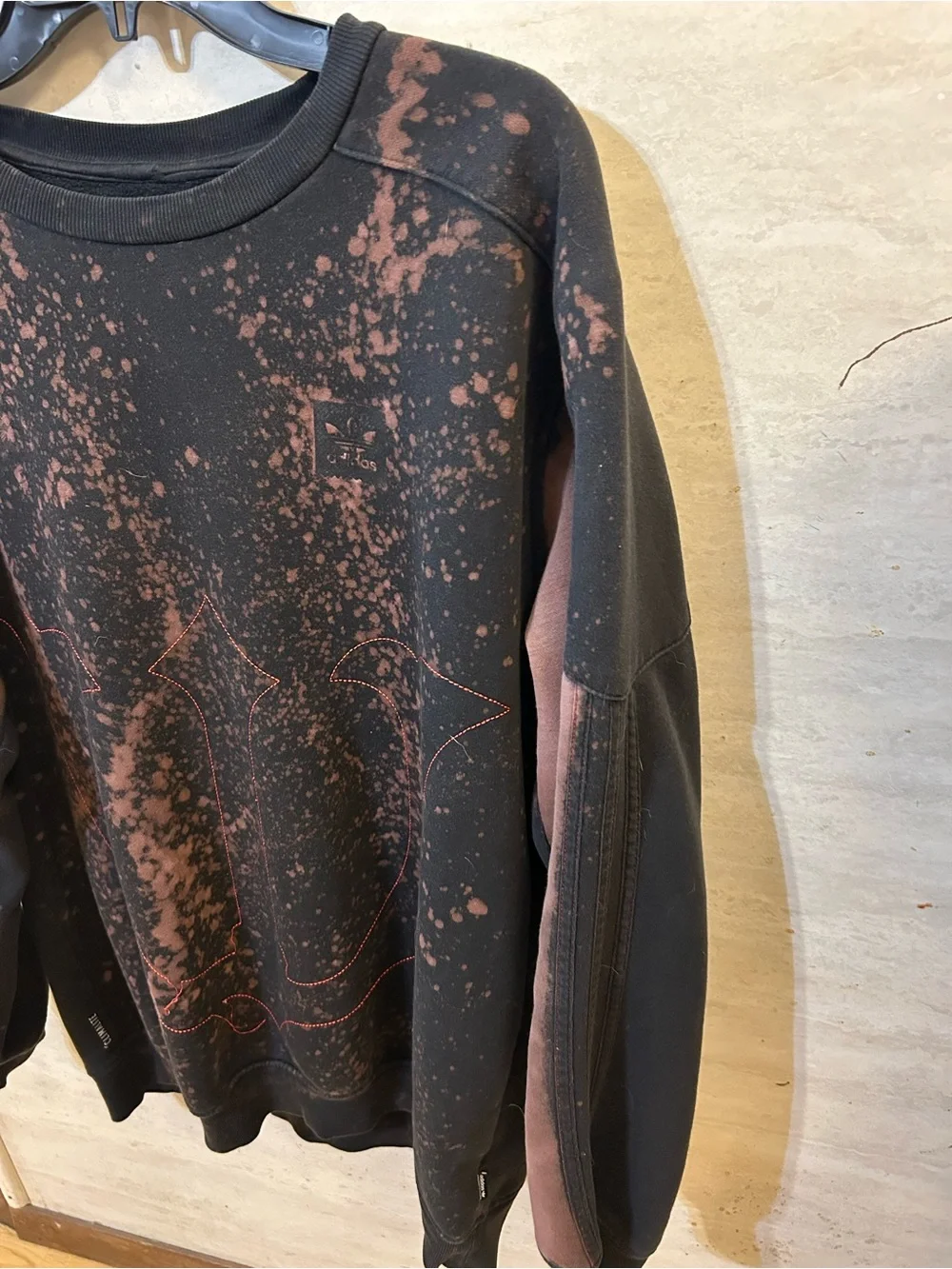 A upcycled, custom bleach-splattered Adidas crewneck sweatshirt